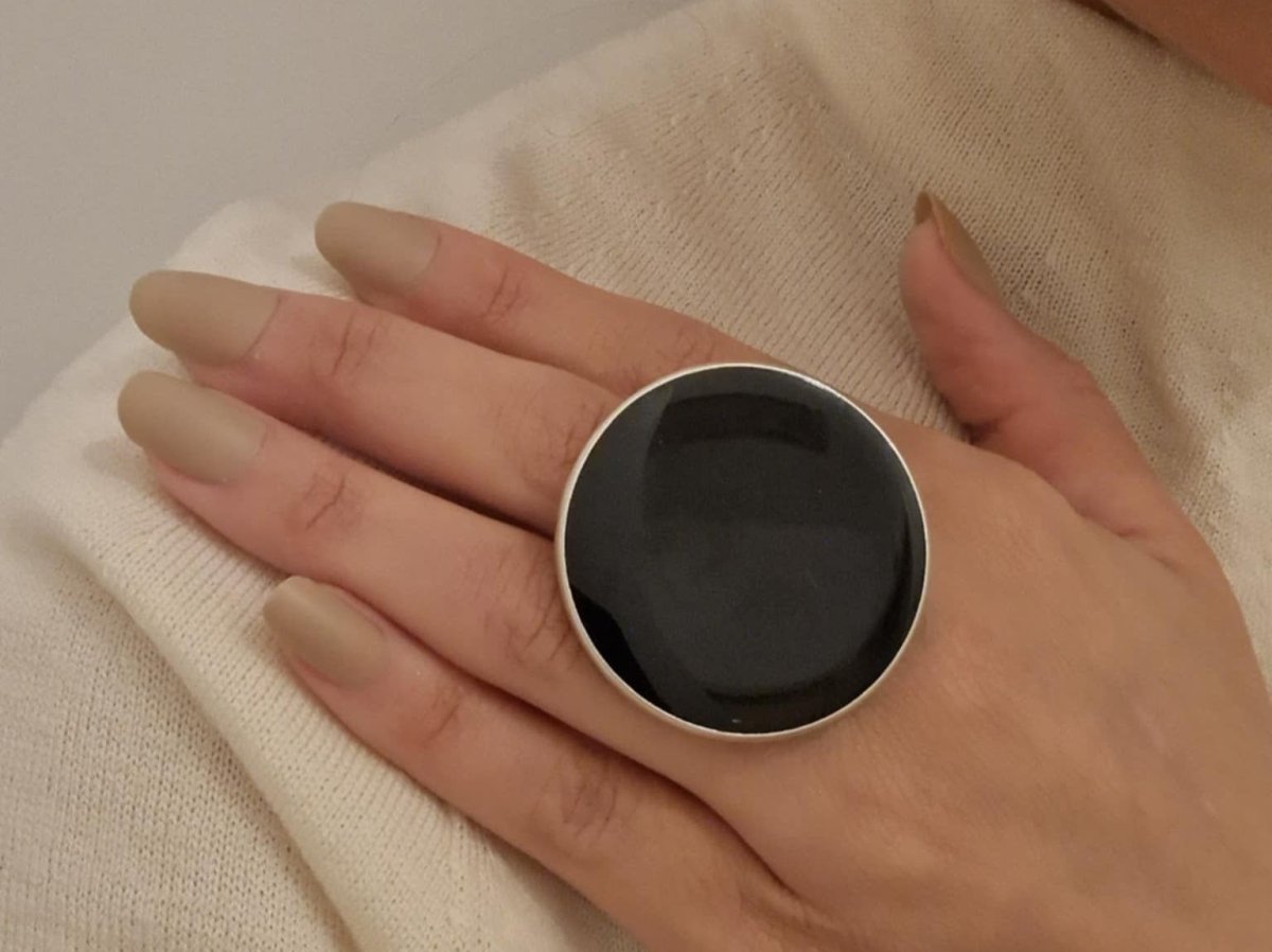 A models hand wearing a large black ring
