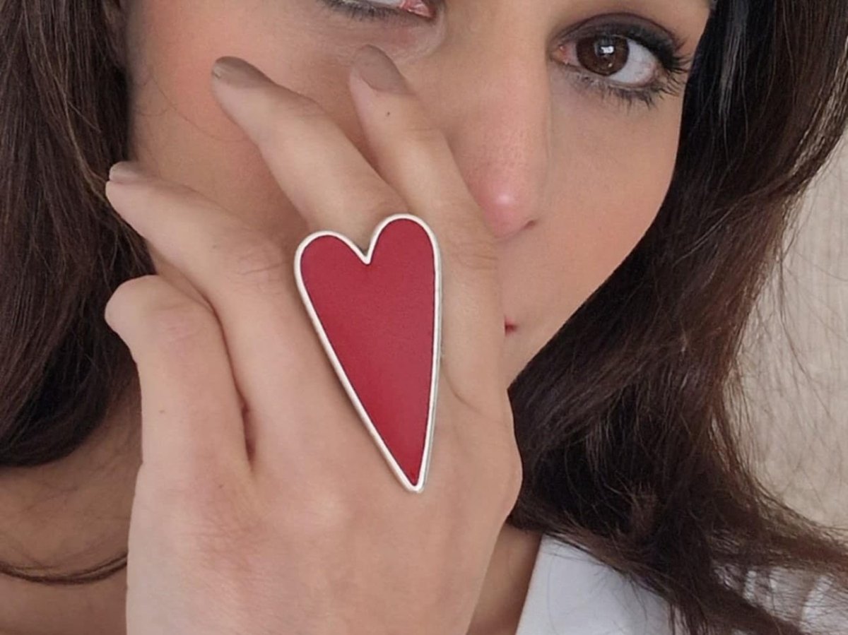 A models hand wearing a large dark red heart shaped ring