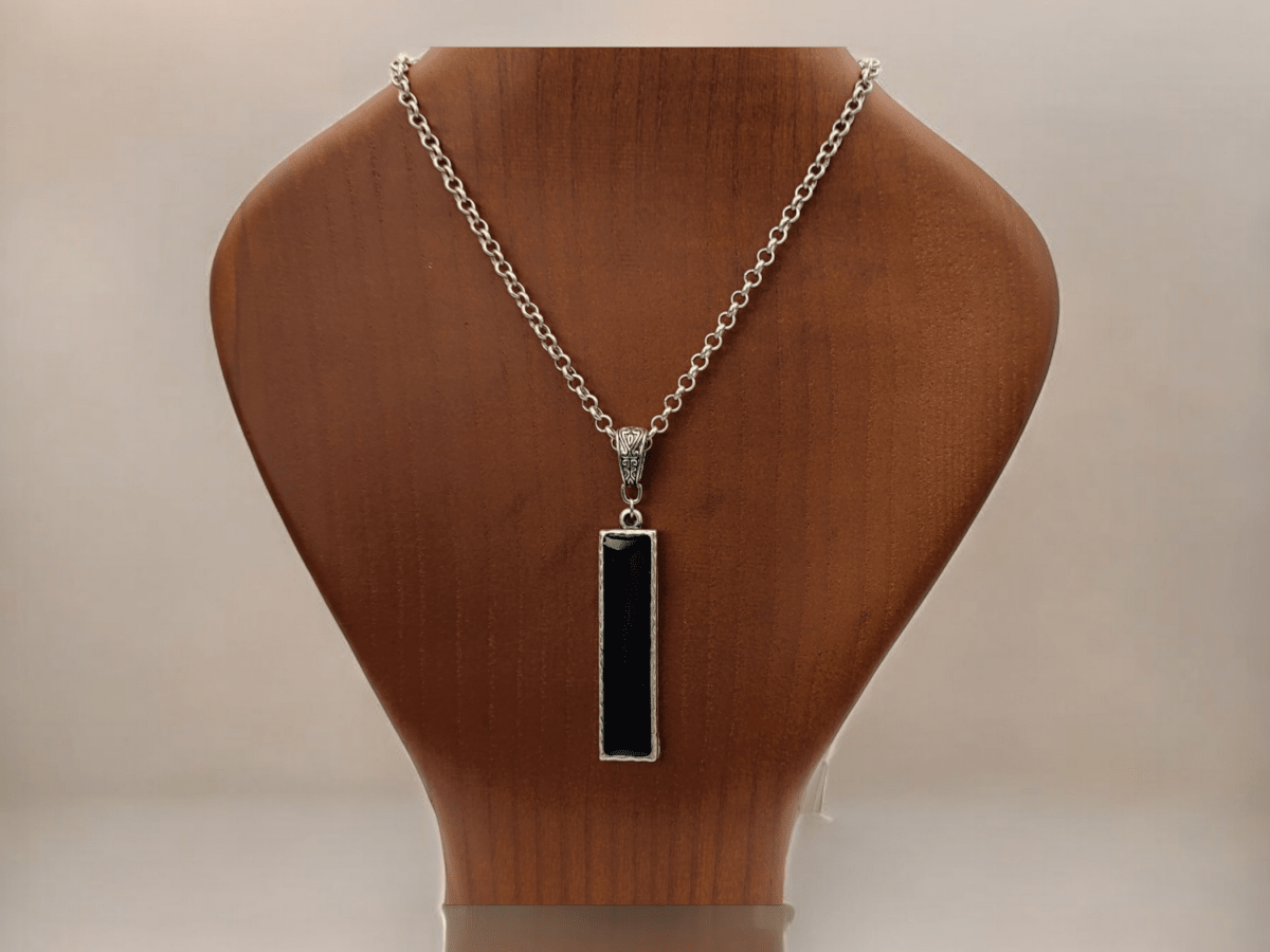 A long rectangular black pendant on a wooden bust