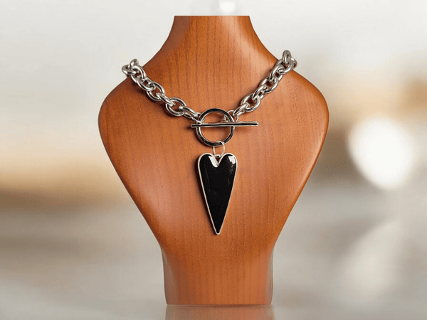 A large black heart pendant on a wooden bust