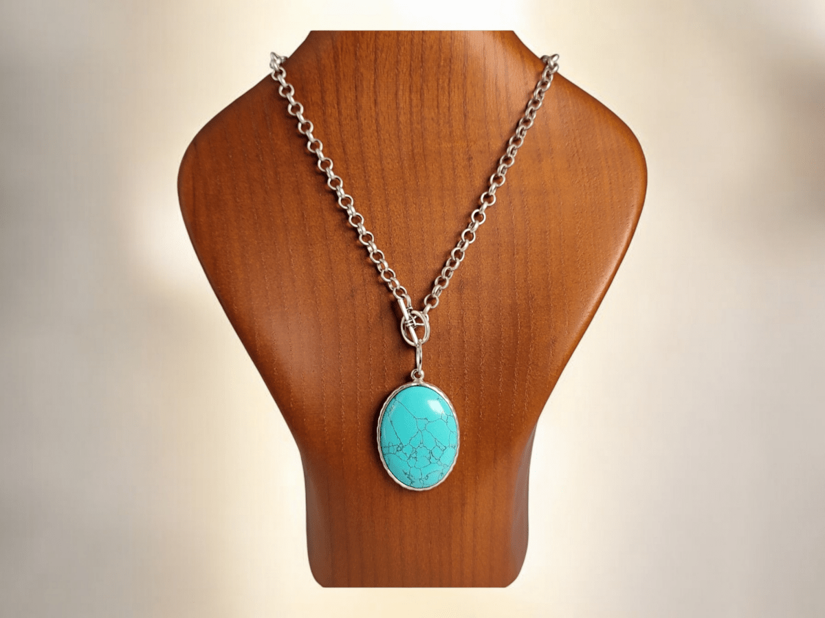 A turquoise pendant on a wooden bust