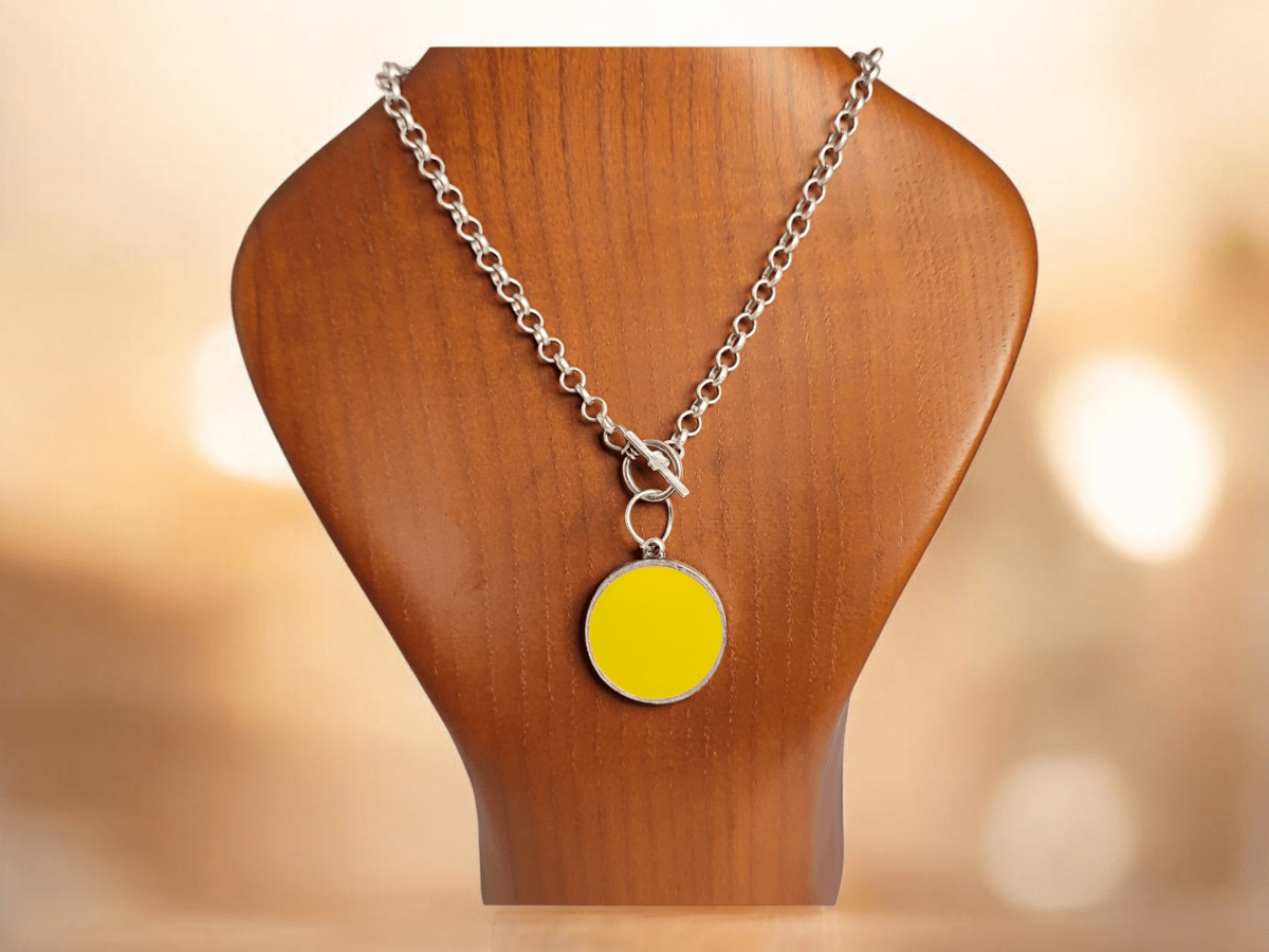 A round yellow pendant on a wooden bust Main image