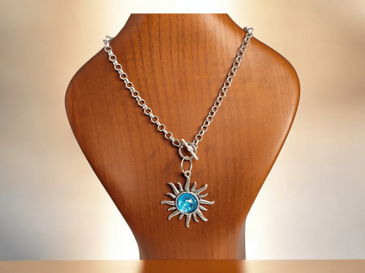 A sun pendant with a blue centre on a wooden bust Main image