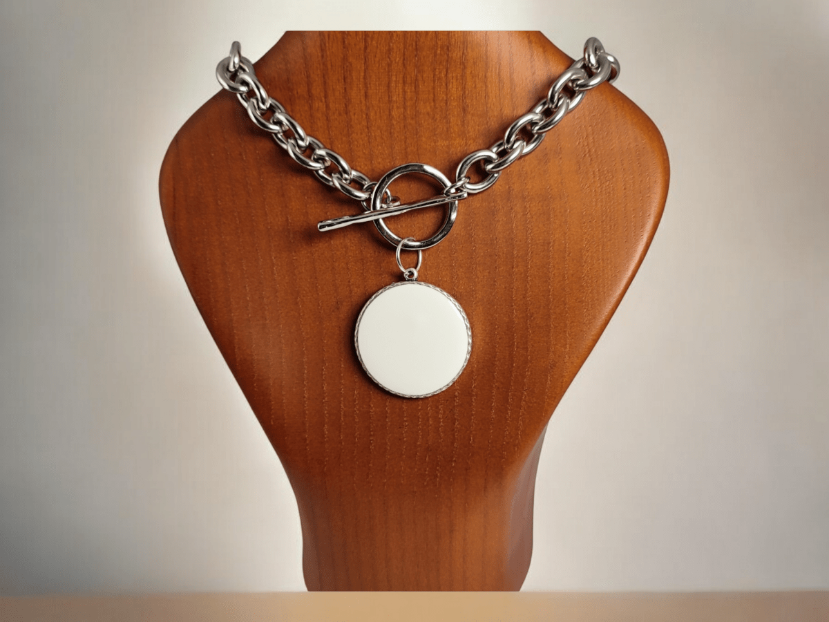 Large round white pendant on a chunky chain on a wooden bust Main image