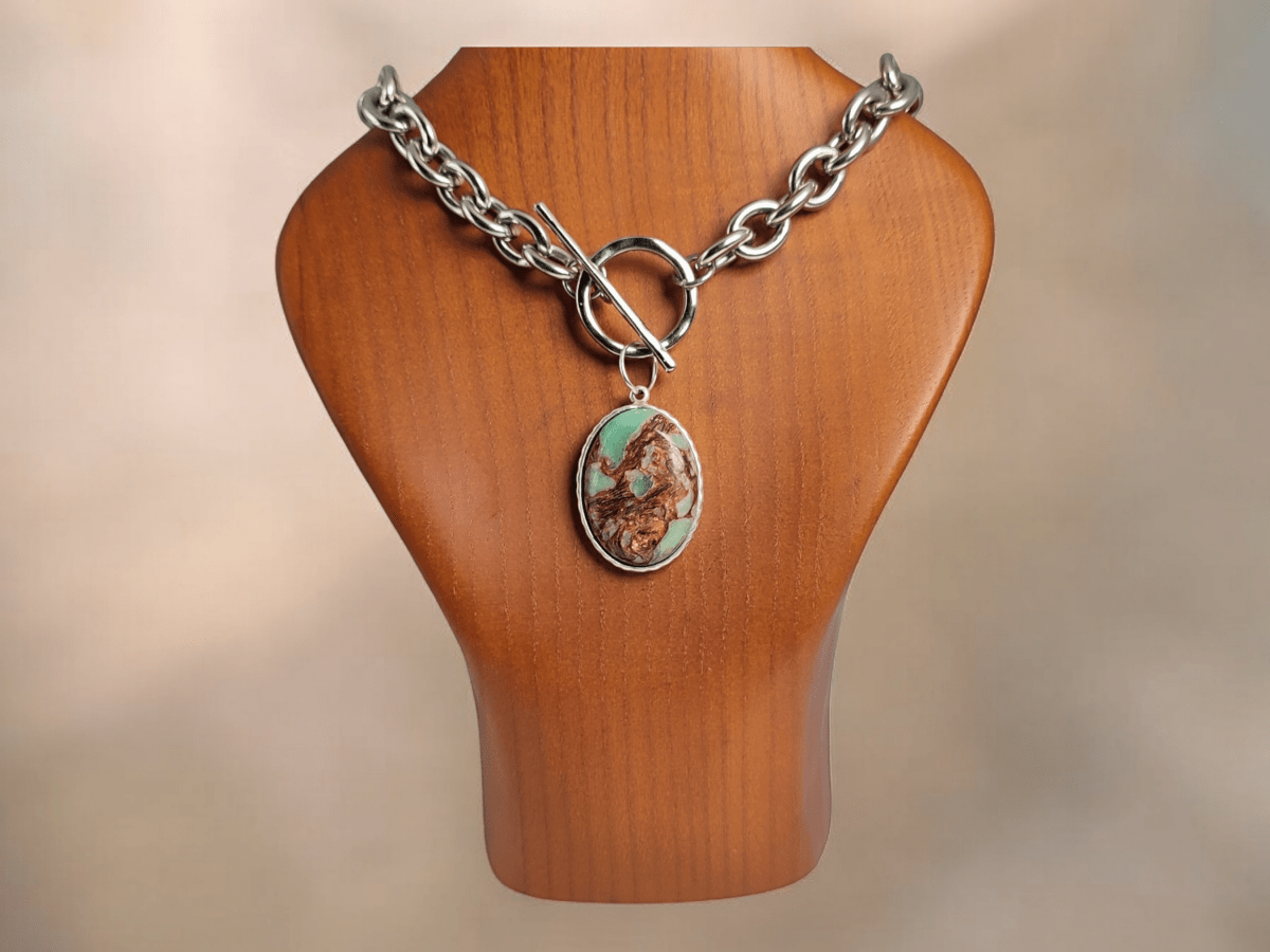 An Imperial Jasper Pendant suspended from a chunky chain on a wooden bust