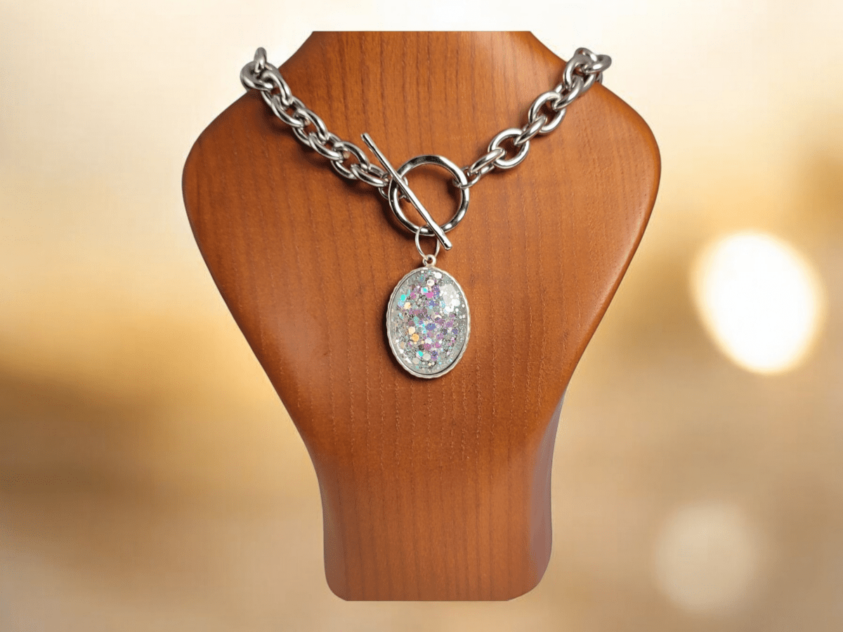 A glitter pendant on a chunky chain on a wooden bust