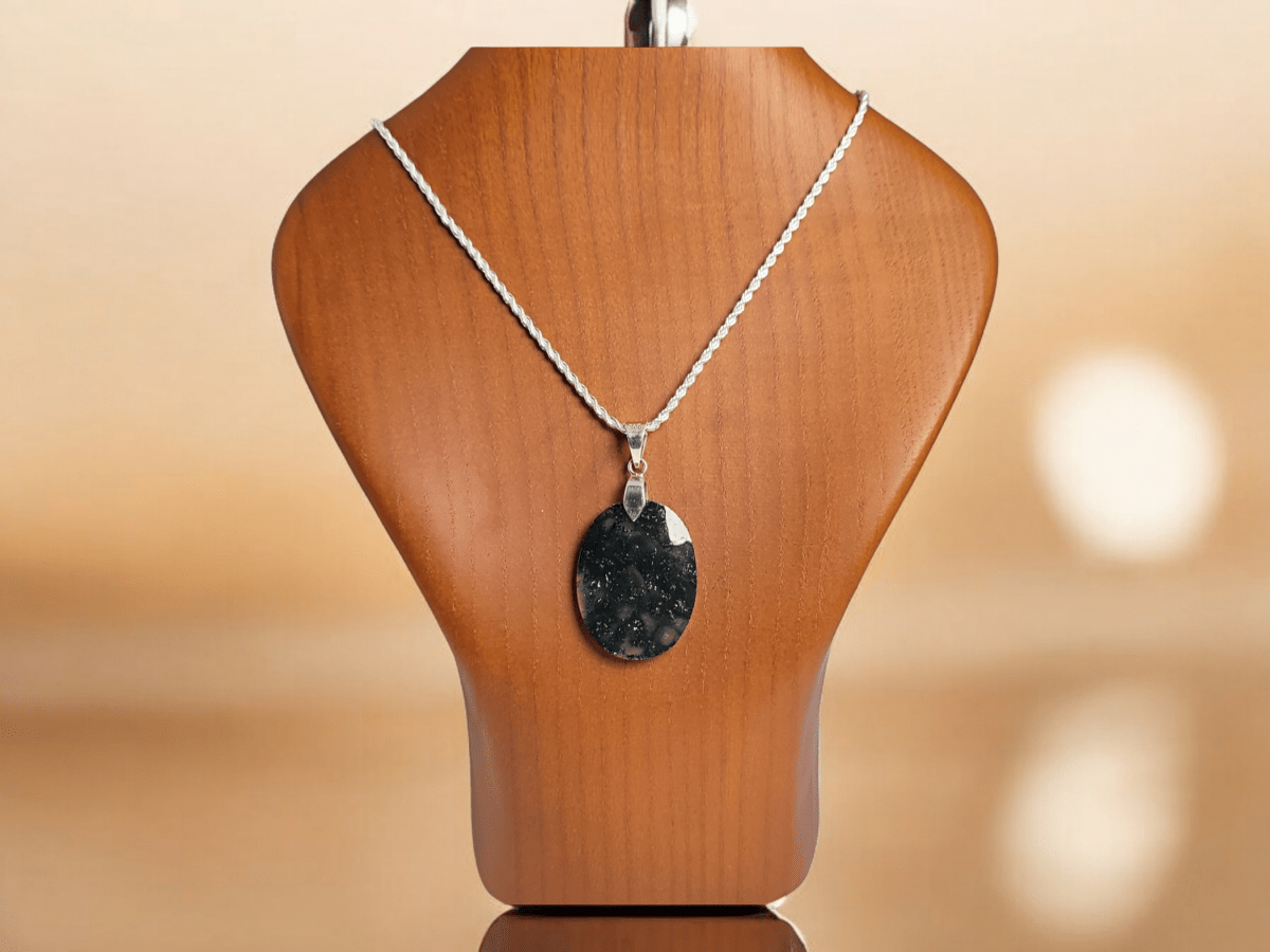 A Dendritic Moss Agate pendant suspended from a silver chain on a wooden bust Main image
