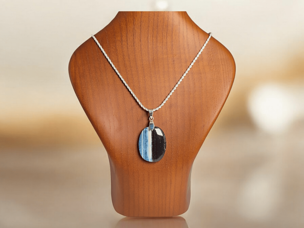 An Opal pendant suspended from a silver chain on a wooden bust