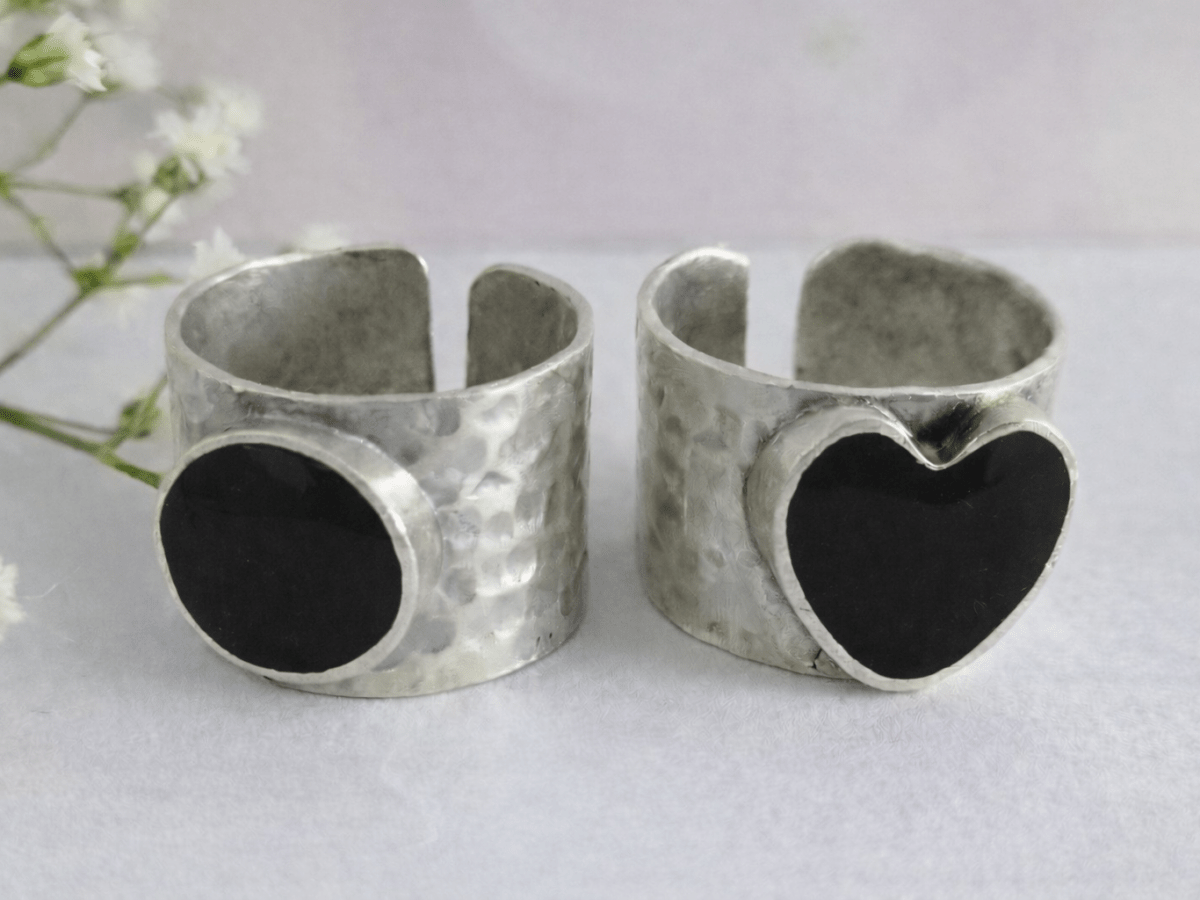 A picture of 2 bands rings, one with a black heart one with a black circle