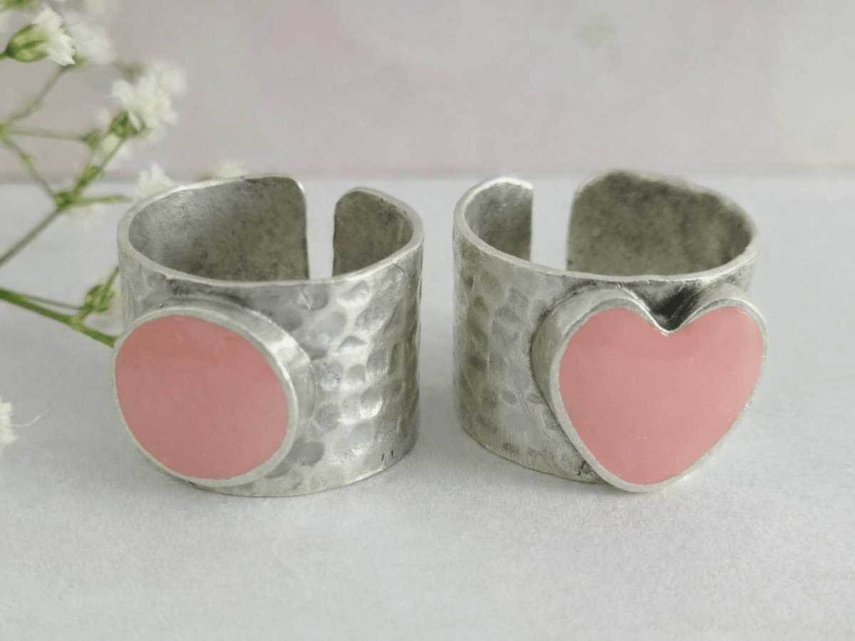 A picture of 2 bands rings, one with a pink heart one with a pink circle