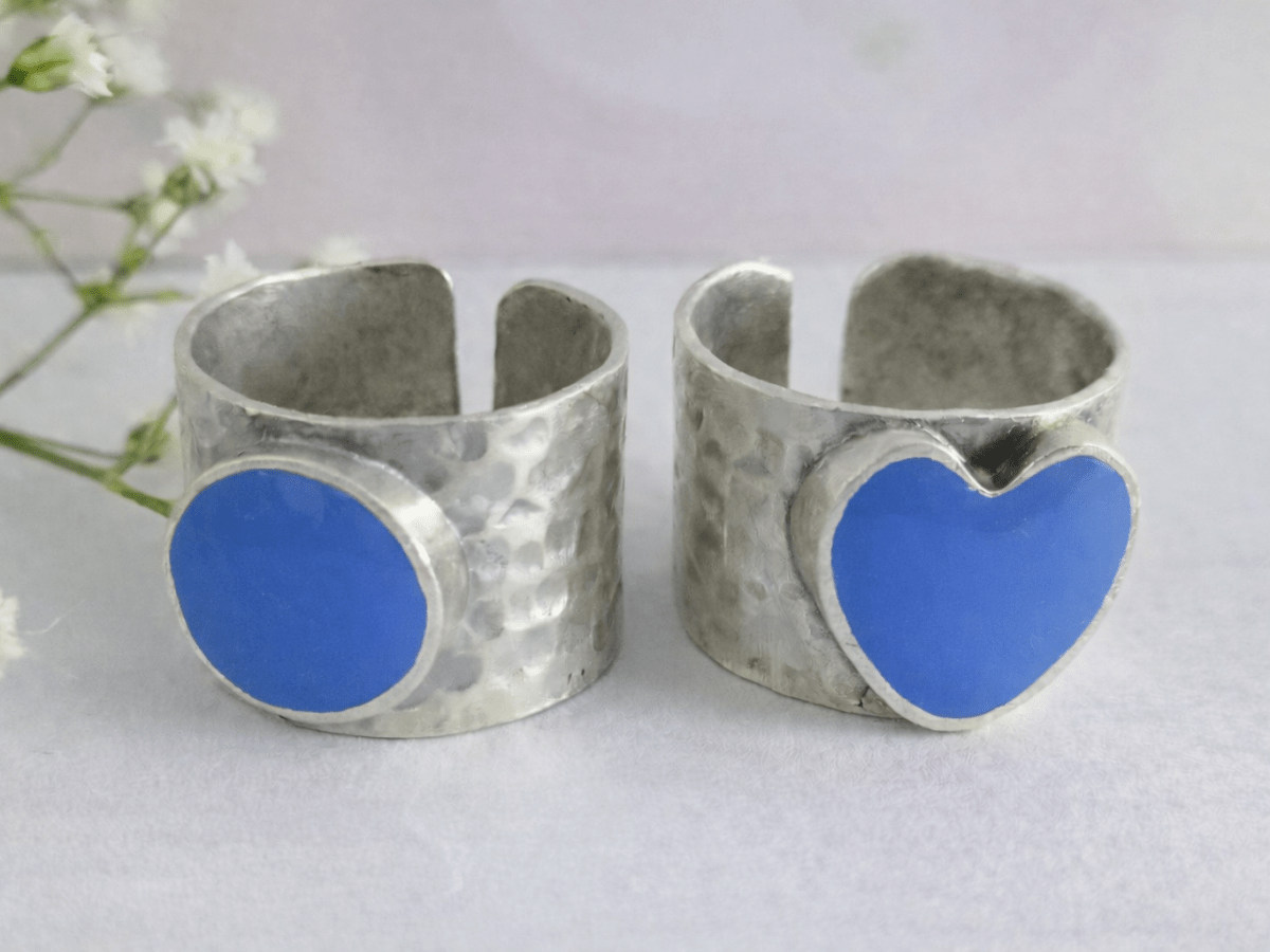 A picture of 2 bands rings, one with a blue heart one with a sblue circle