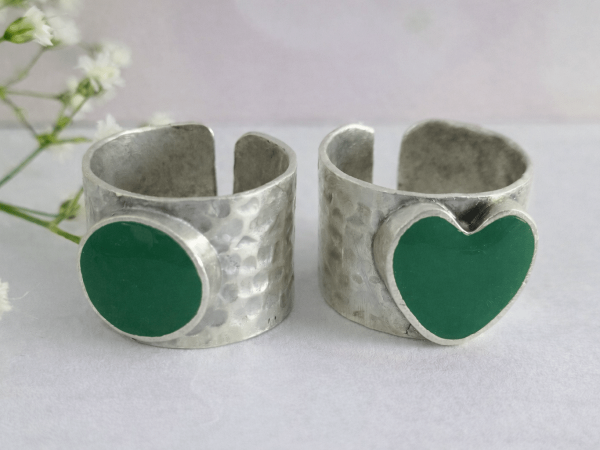 A picture of 2 bands rings, one with a  green heart one with a green circle