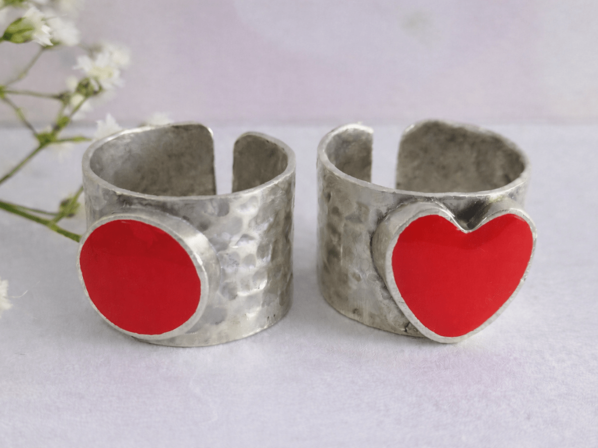 A picture of 2 bands rings, one with a red heart one with a red circle