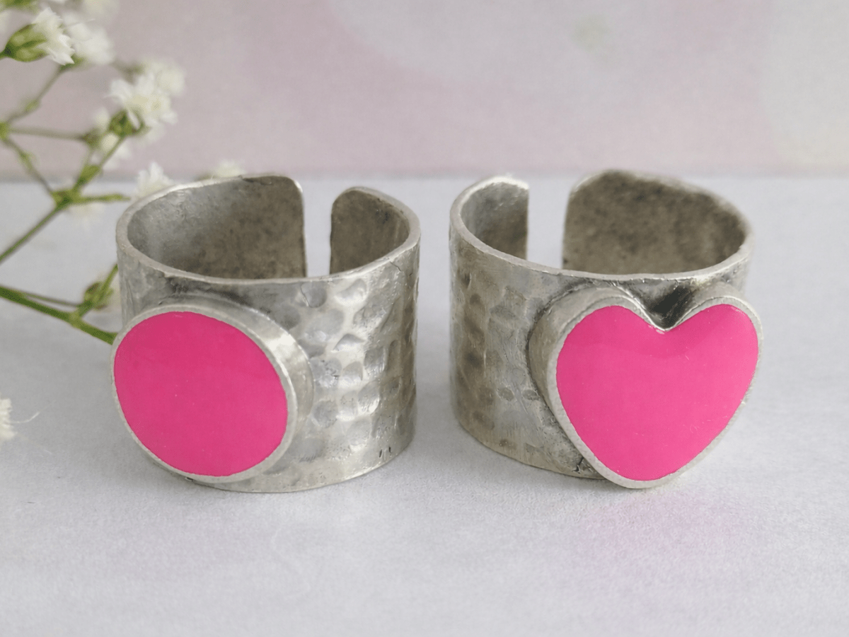 A picture of 2 bands rings, one with a bright pink heart one with a bright pink circle