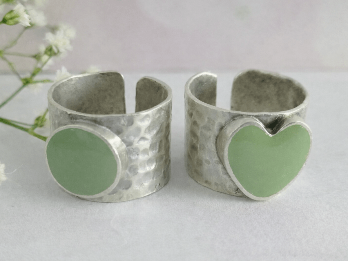 A picture of 2 bands rings, one with a sage green heart one with a sage green circle