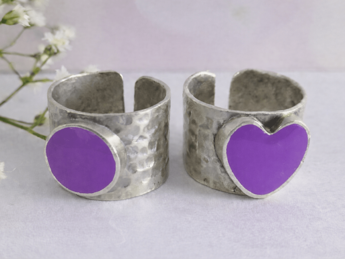 A picture of 2 bands rings, one with a violet heart one with a violet circle
