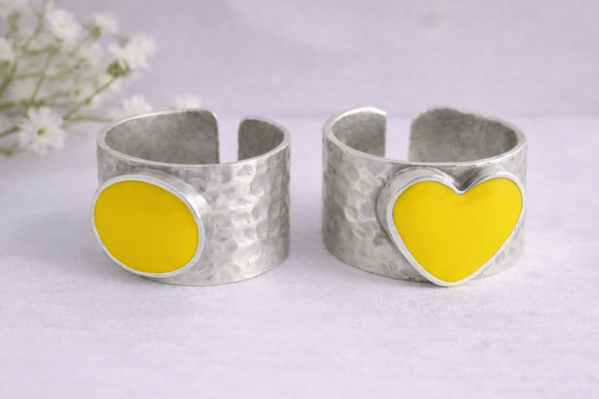 A picture of 2 bands rings, one with a yellow heart one with a yellow circle