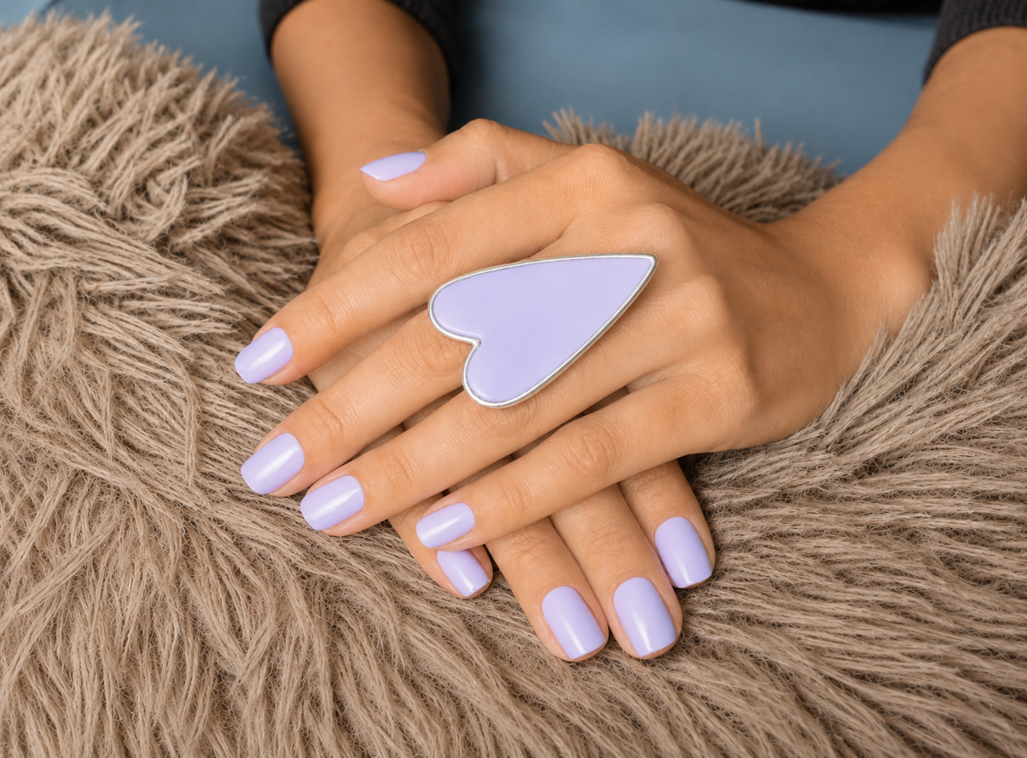 Hand wearing a heart-shaped ring on a textured surface