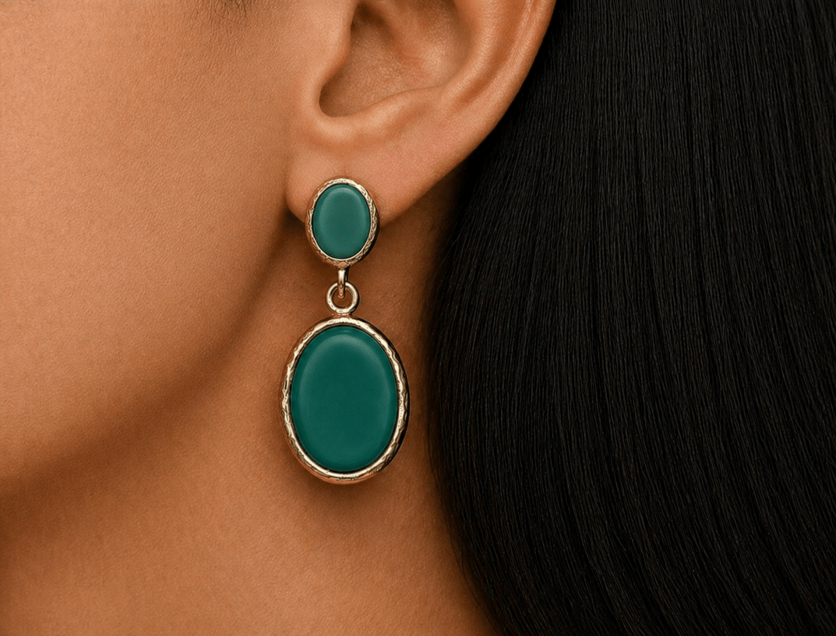A model wearing some oval green dangle drop earrings
