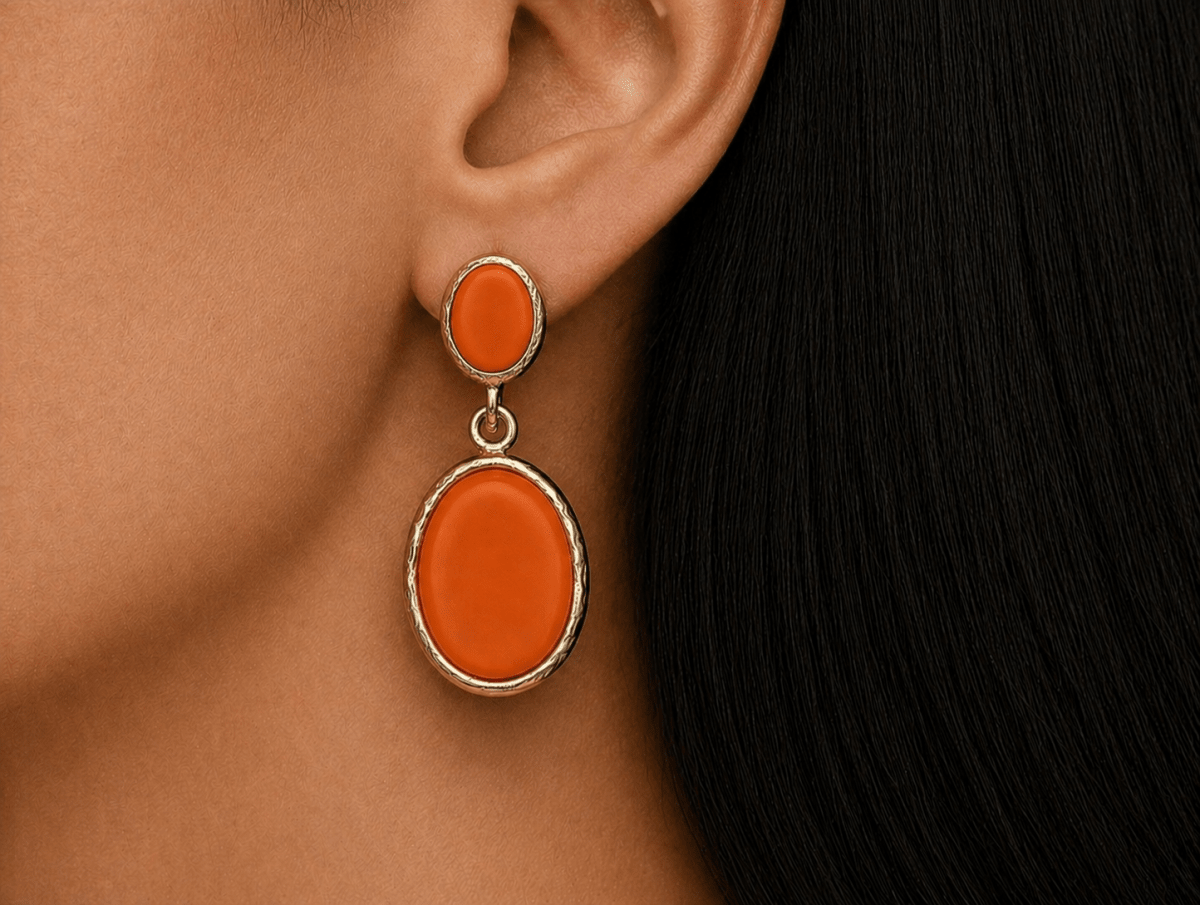 A model wearing some oval orange dangle drop earrings