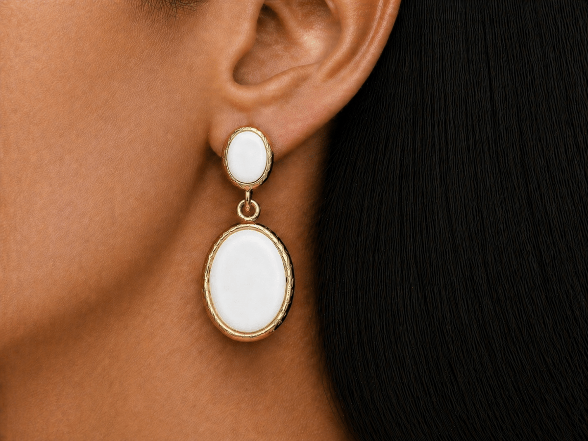 A model wearing some oval white dangle drop earrings