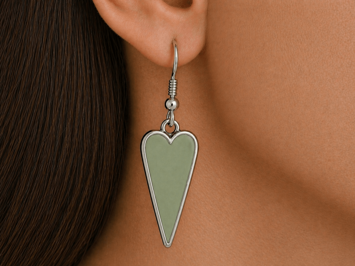 A model wearing some sage green heart shaped earrings