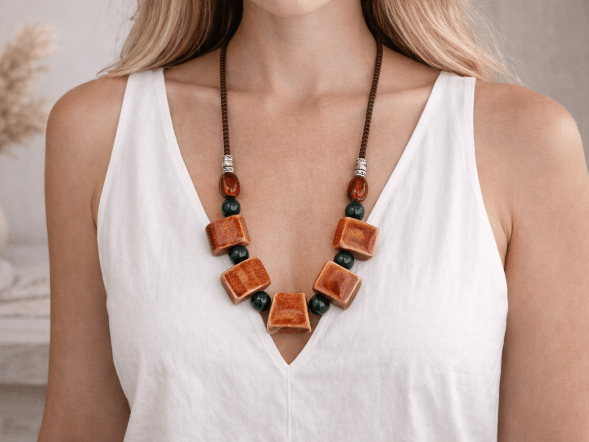 A model with a white top wearing a red ceramic necklace 