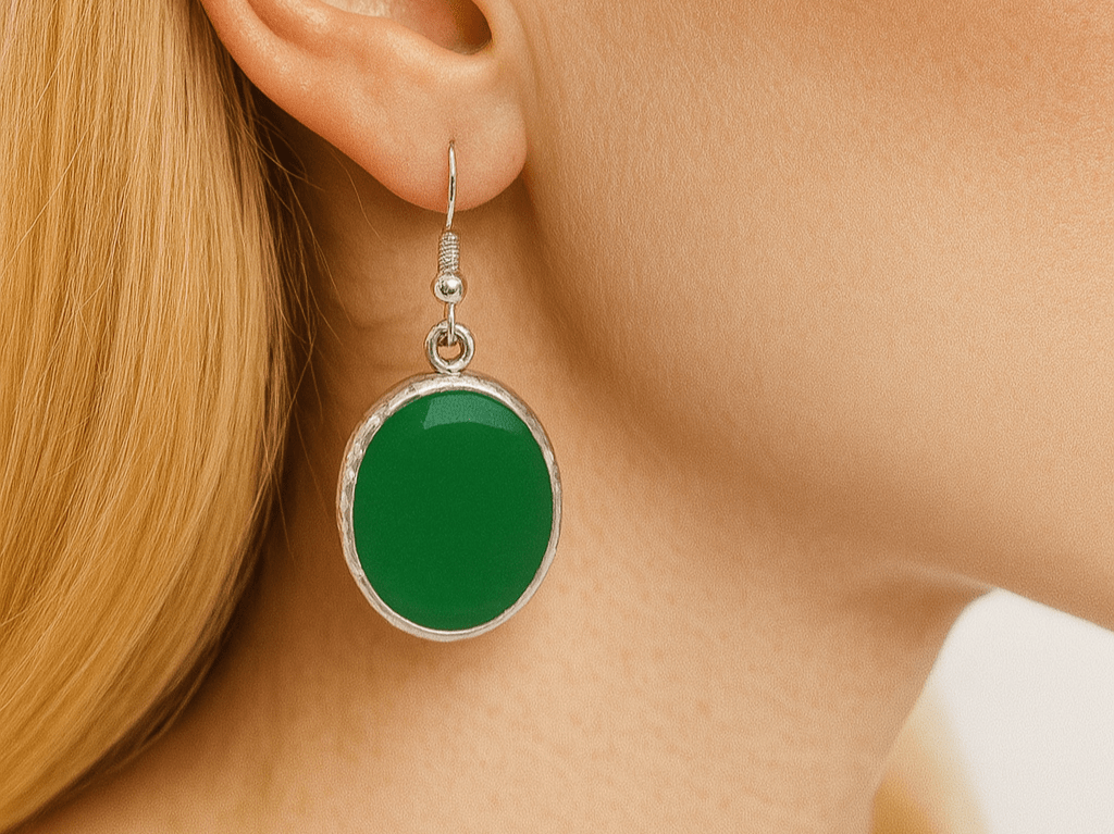 Green earring worn by a person with blonde hair.