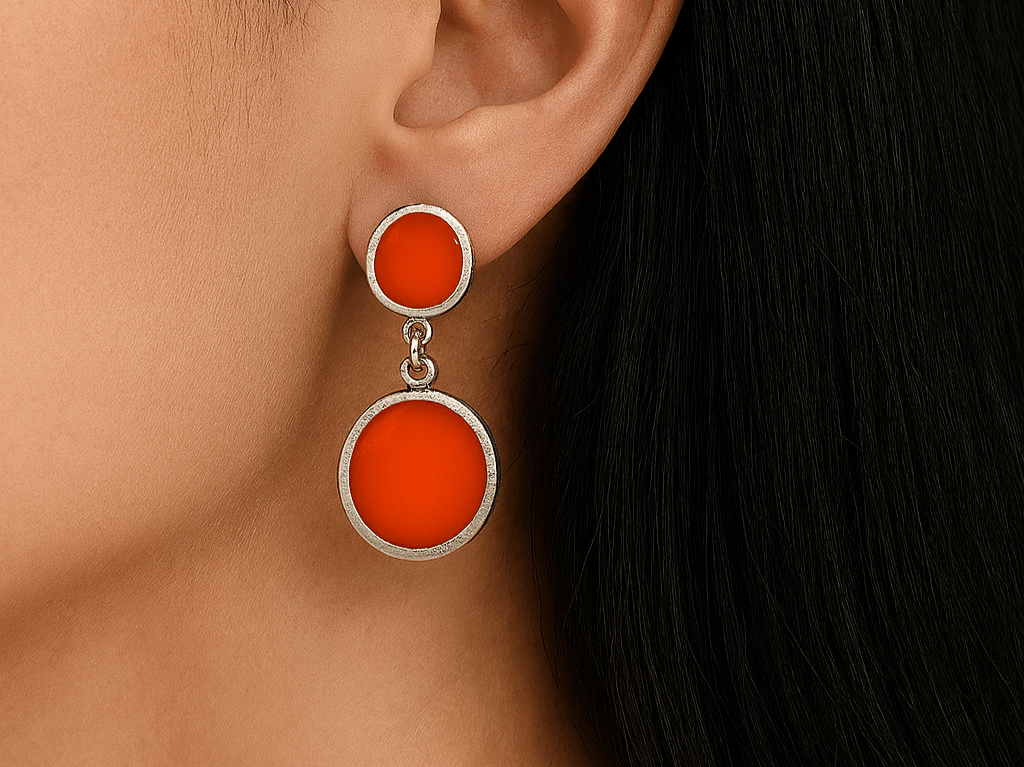 A model wearing some round orange dangle drop earrings