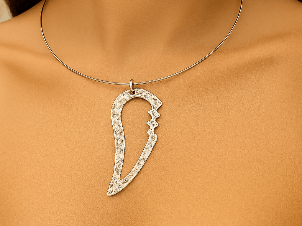 An abstract silver pendant on a stainless steel torque choker