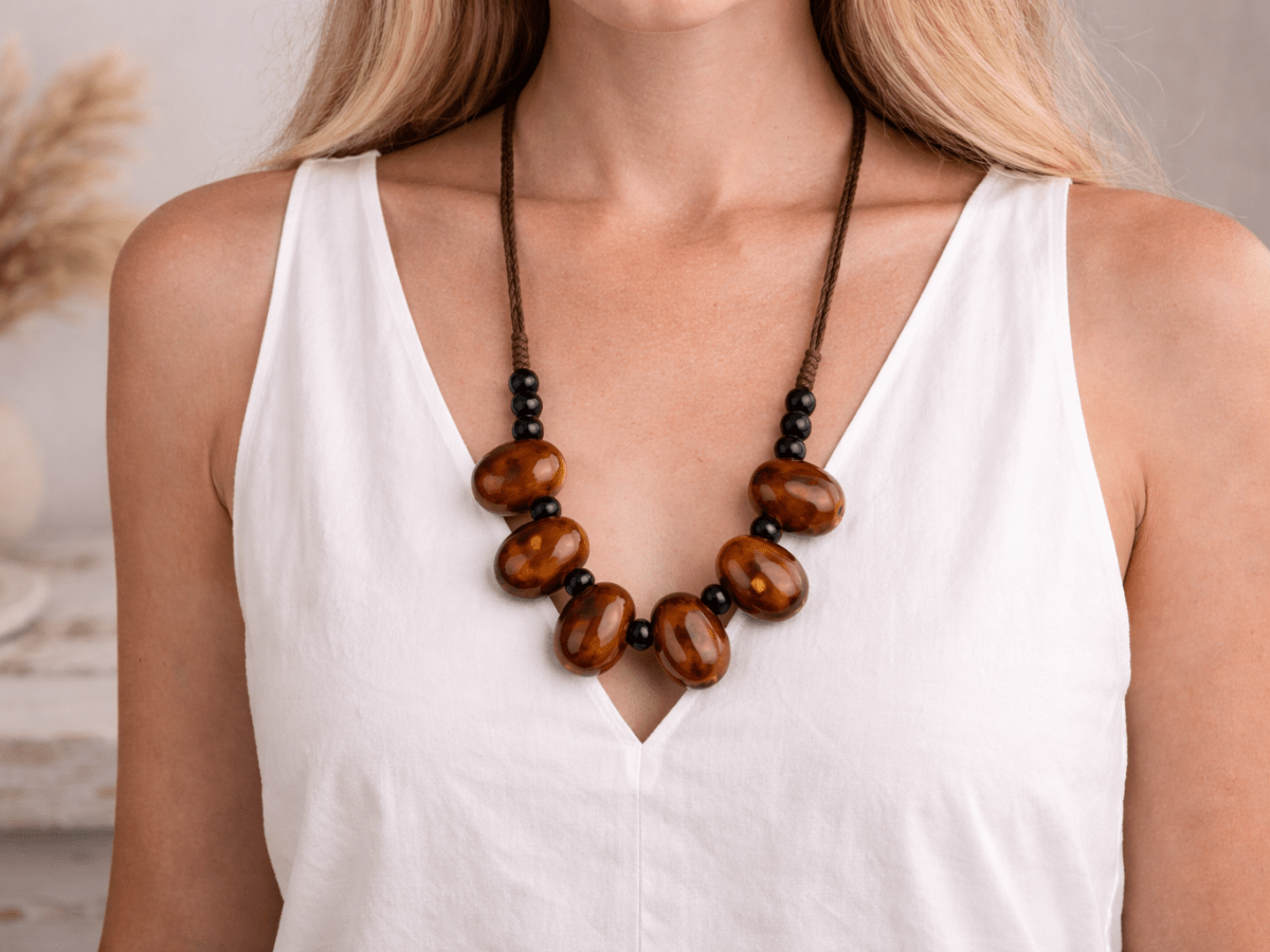 A model with a white top wearing a bronze coloured ceramic bead necklace Main image