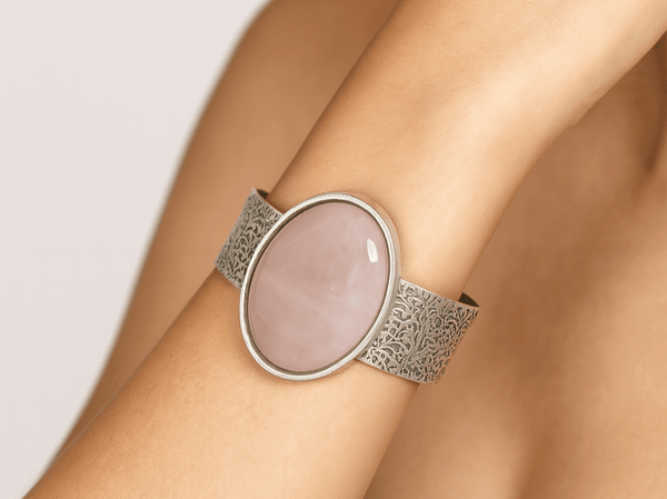 a chunky rose quartz cuff bracelet worn on a models wrist