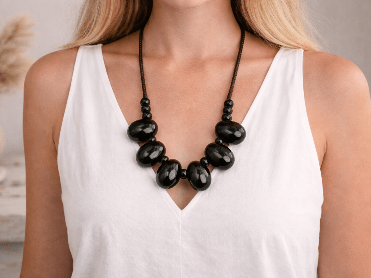 A long black ceramic necklace being worn by a model wearing a white top Main image