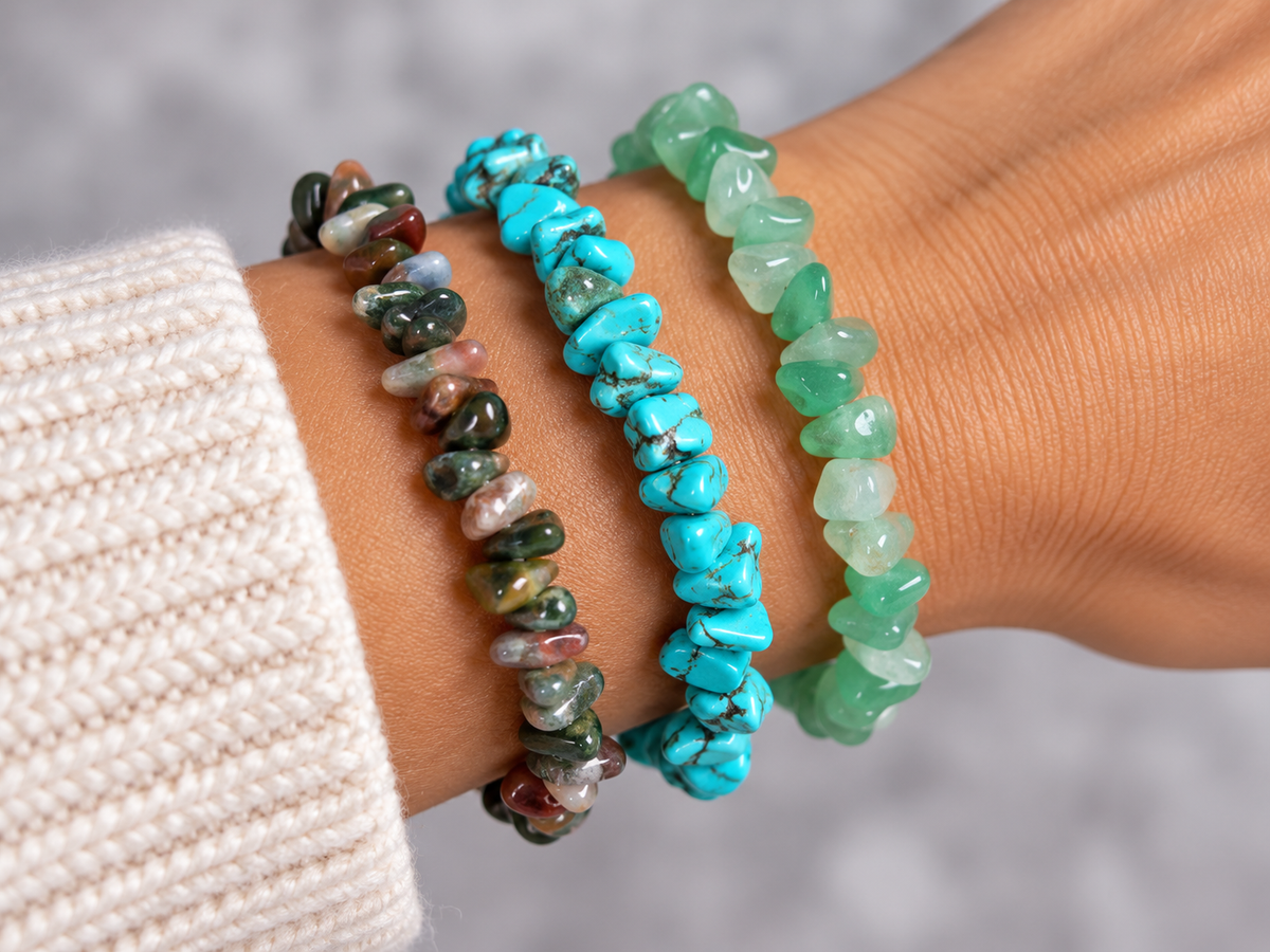 a close up of a models wrist wearing 3 gemstone bracelets of turquoise, aventurine and indian agate