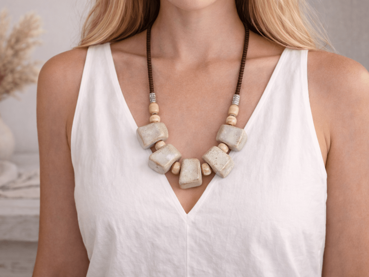 A model wearing a white top wearing a neutral beige ceramic necklace Main image