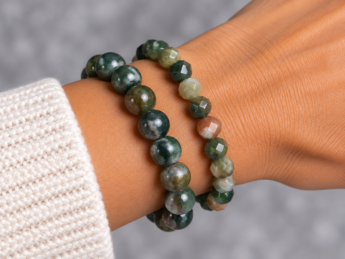 close u of a wrist wearing 2 indian Agate bracelets against a grey backround