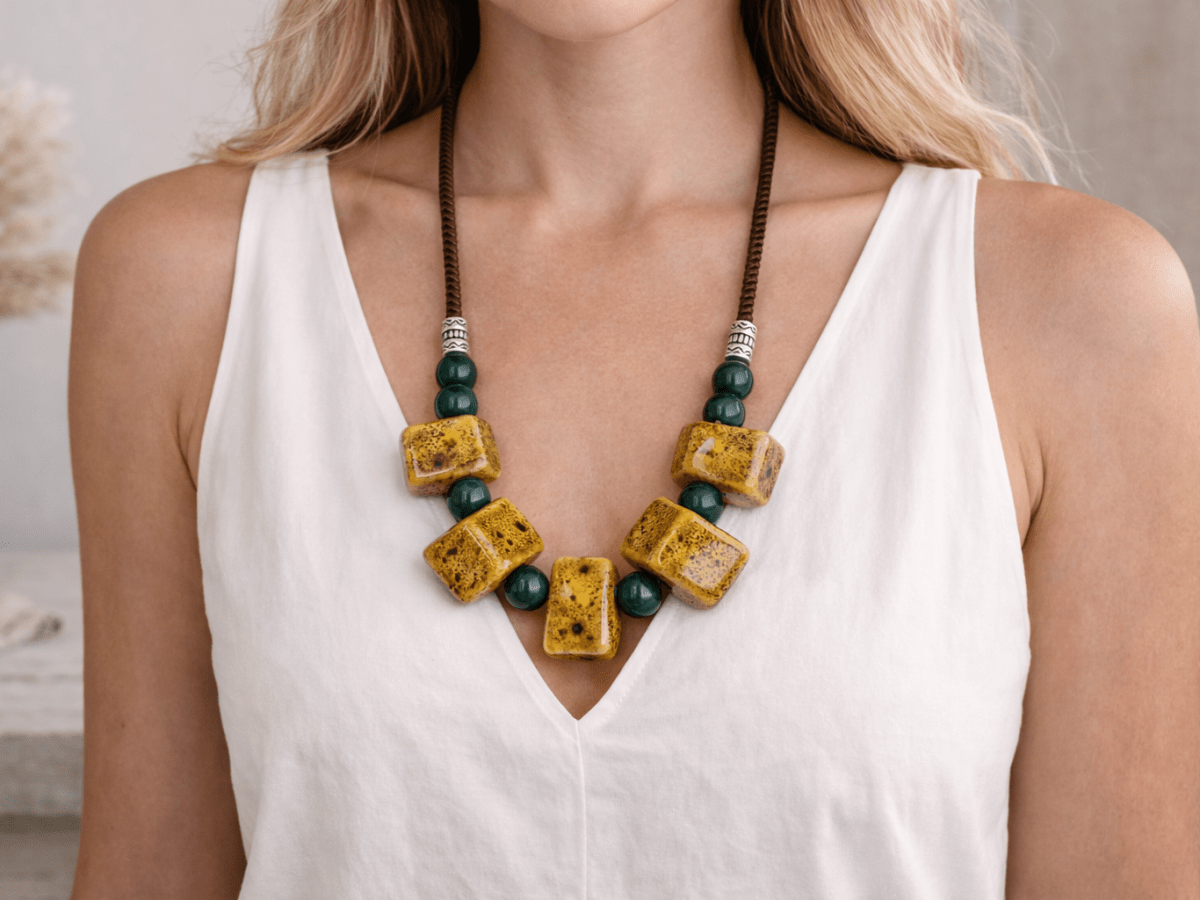 A model with a white top wearing a mustard yellow ceramic long necklace Main image
