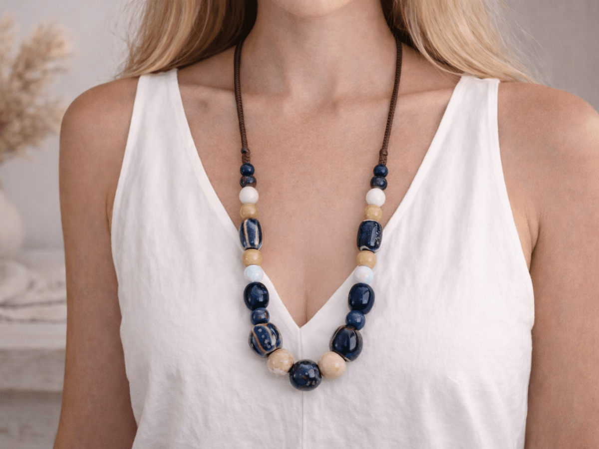 A model with a white top wearing a blue and beige ceramic necklace Main image
