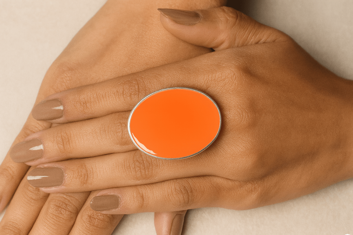 A models hands wearing a neon orange oval ring