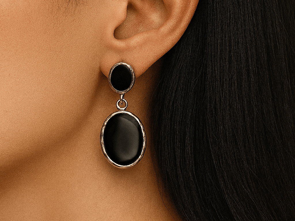 Black earrings with gold accents worn by a person with dark hair.