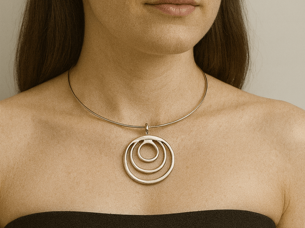 A model with brown hair and wearing a black top, modelling a circular torque pendant choker