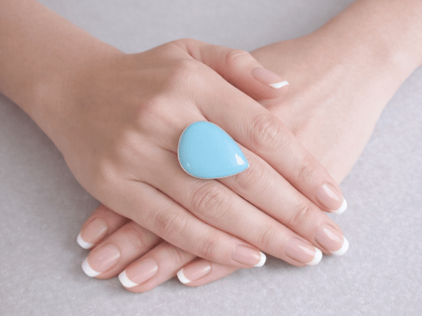 A bold blue chalcedony ring with a smooth, solid colour that brings a clean and modern look. Worn on a models hand