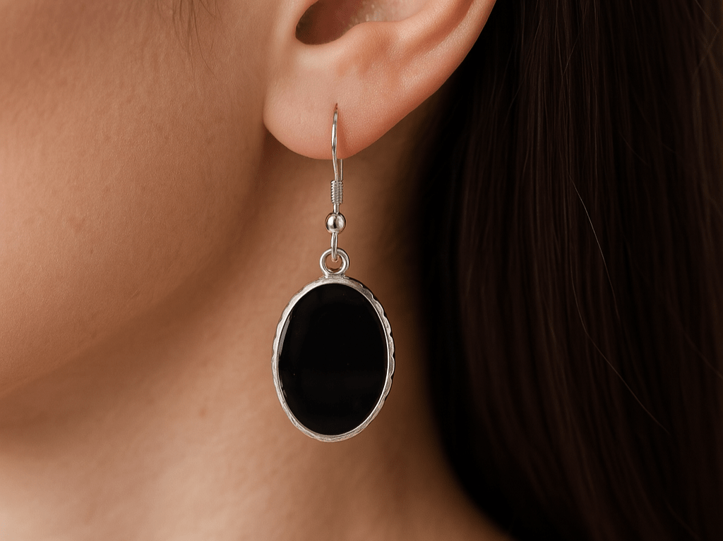 Black oval earring on a person's ear with a dark background