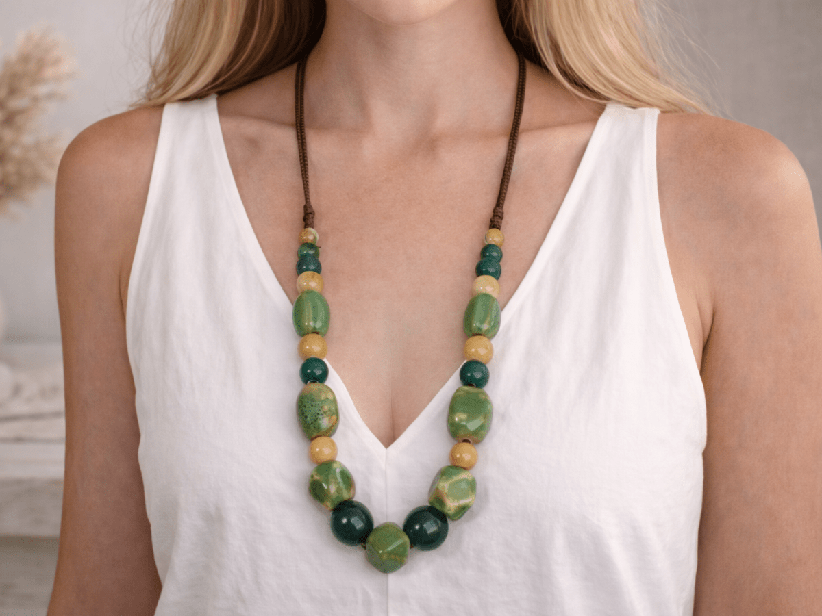 A model with a white top wearing a green and beige ceramic beaded necklace Main image