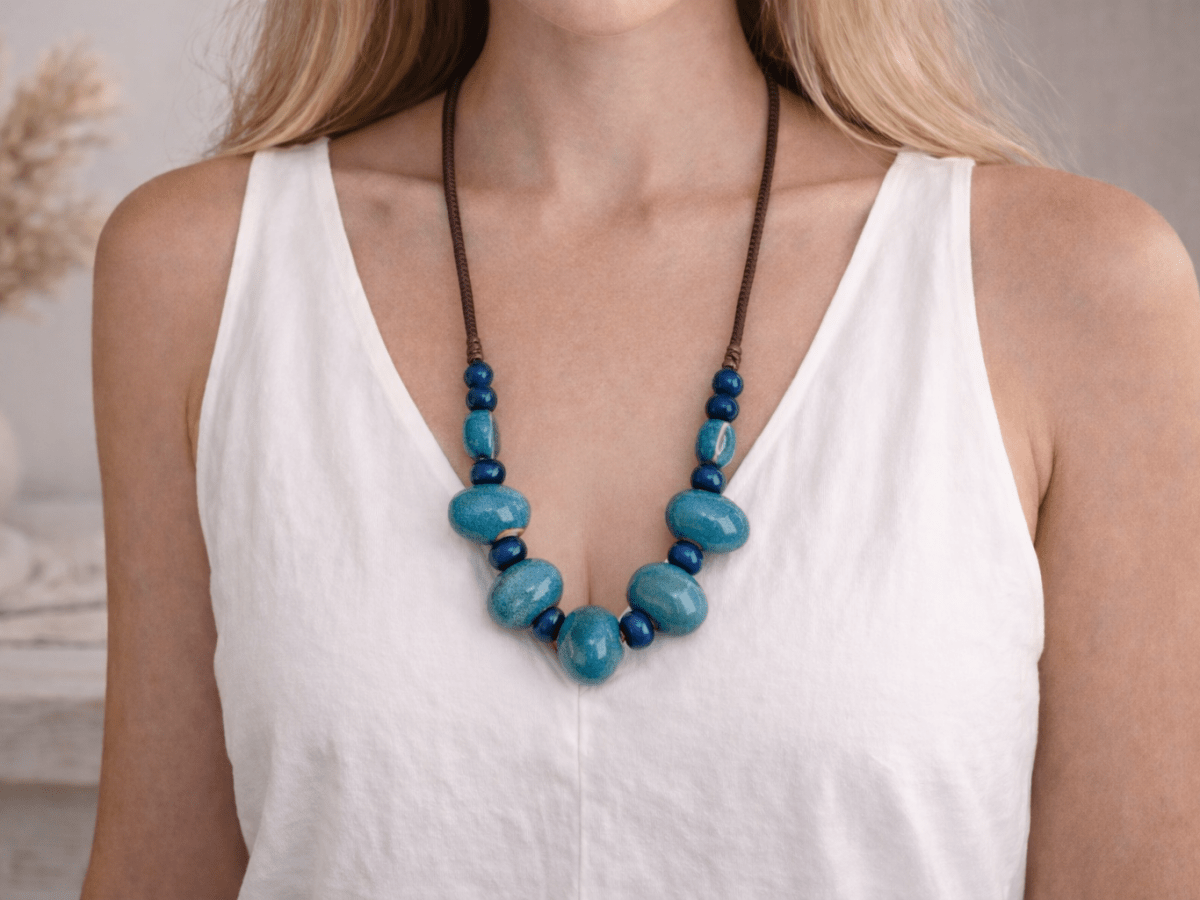 A model with a white top wearing a blue ceramic necklace Main image