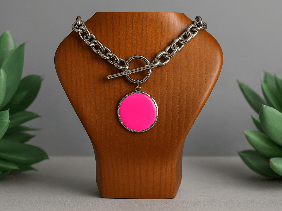 A large neon pink pendant on a chunky chain displayed on a wooden bust Main image