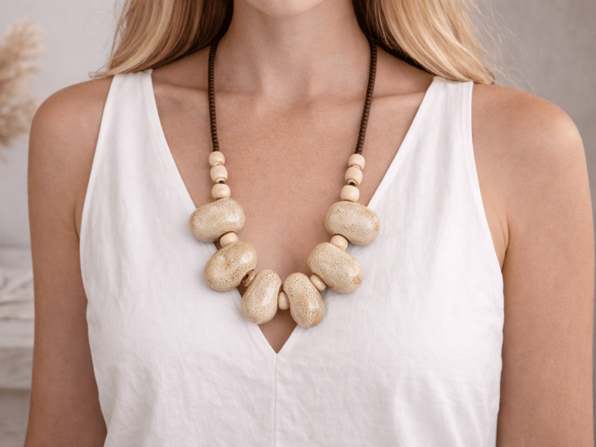 A model with a white top wearing a neutral beige ceramic necklace Main image