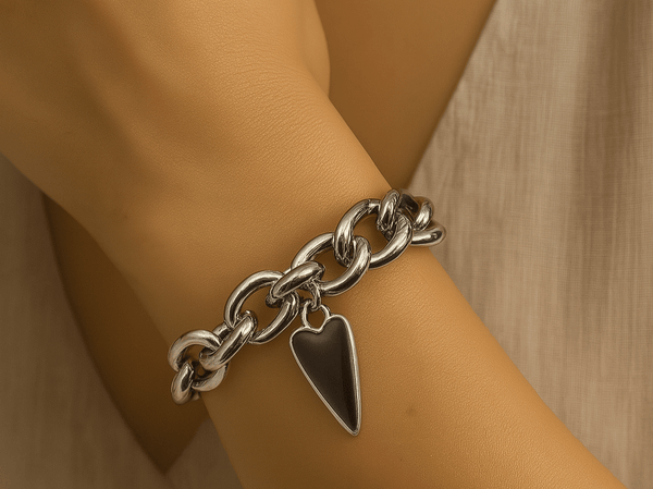 a chunky charm bracelet featuring a black heart charm worn on a models wrist