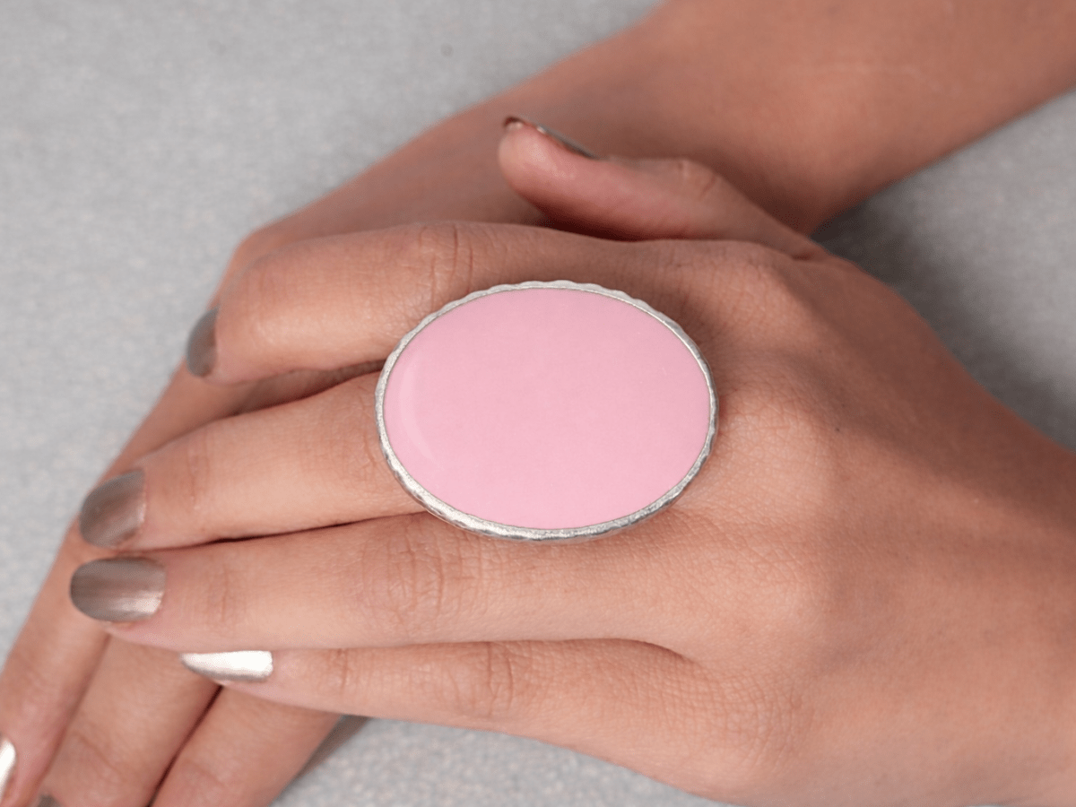 A models hand wearing a pale pink oval ring