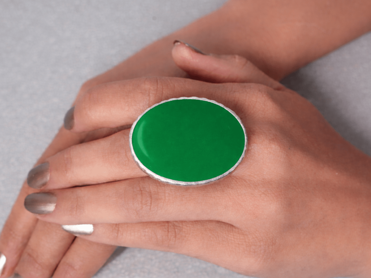 A models hand wearing a green oval ring